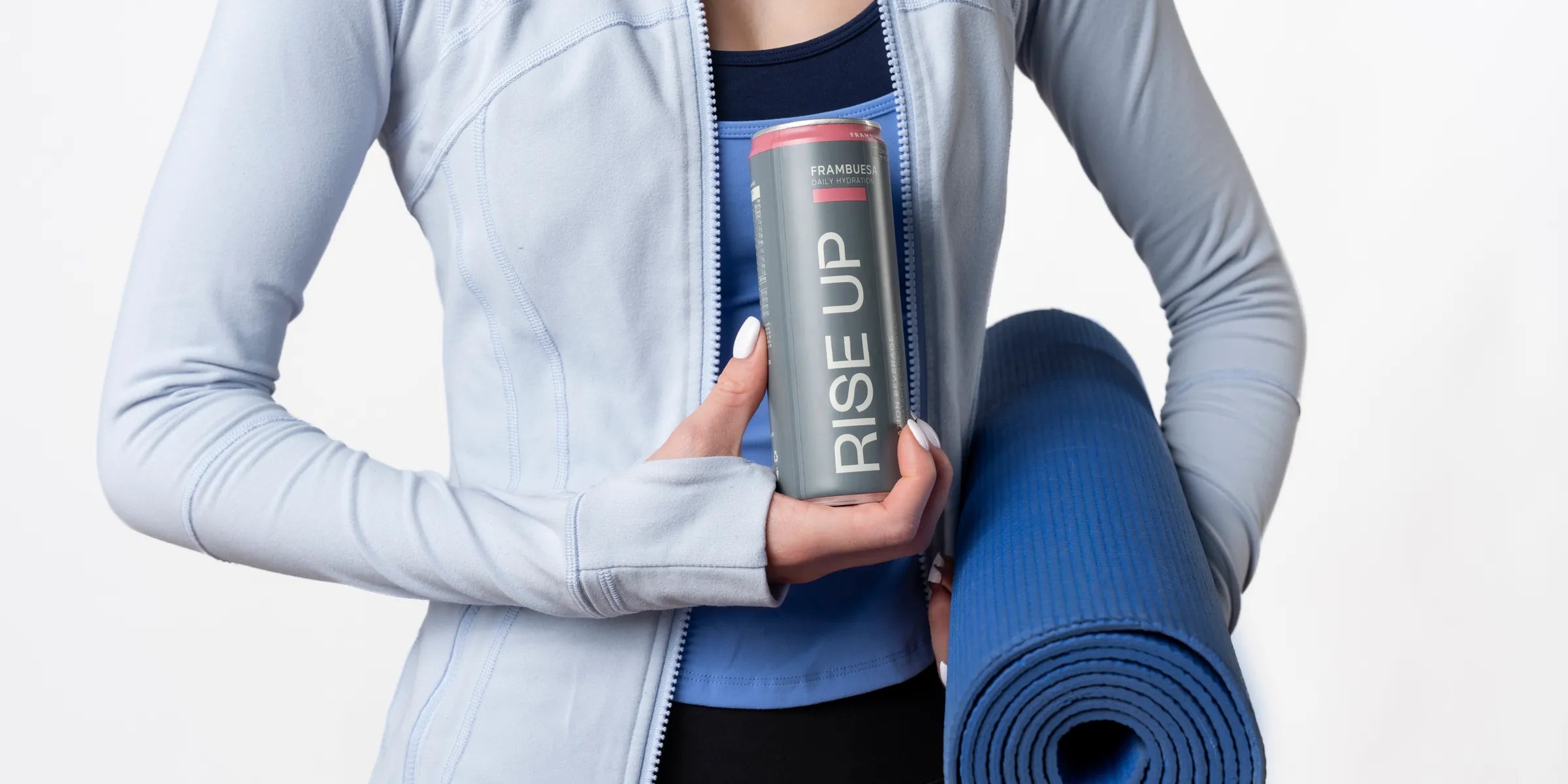 Persona con ropa deportiva sosteniendo una lata Rise Up y un tapete de yoga
